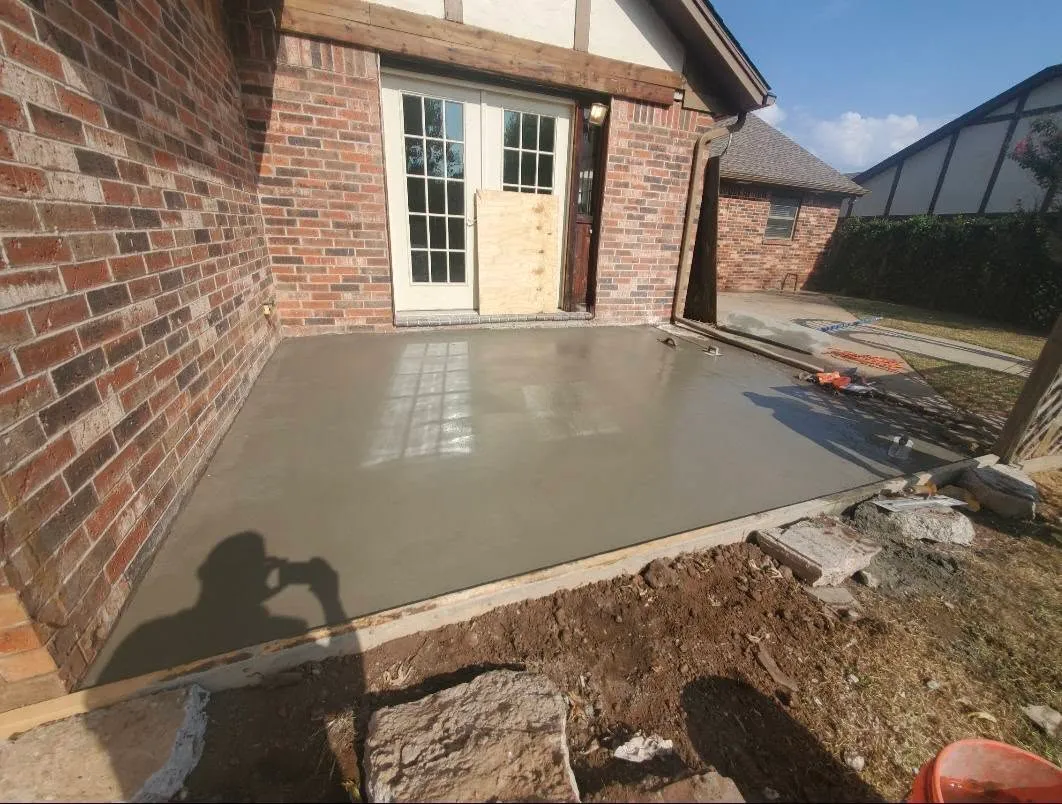 New concrete patio poured behind a brick home