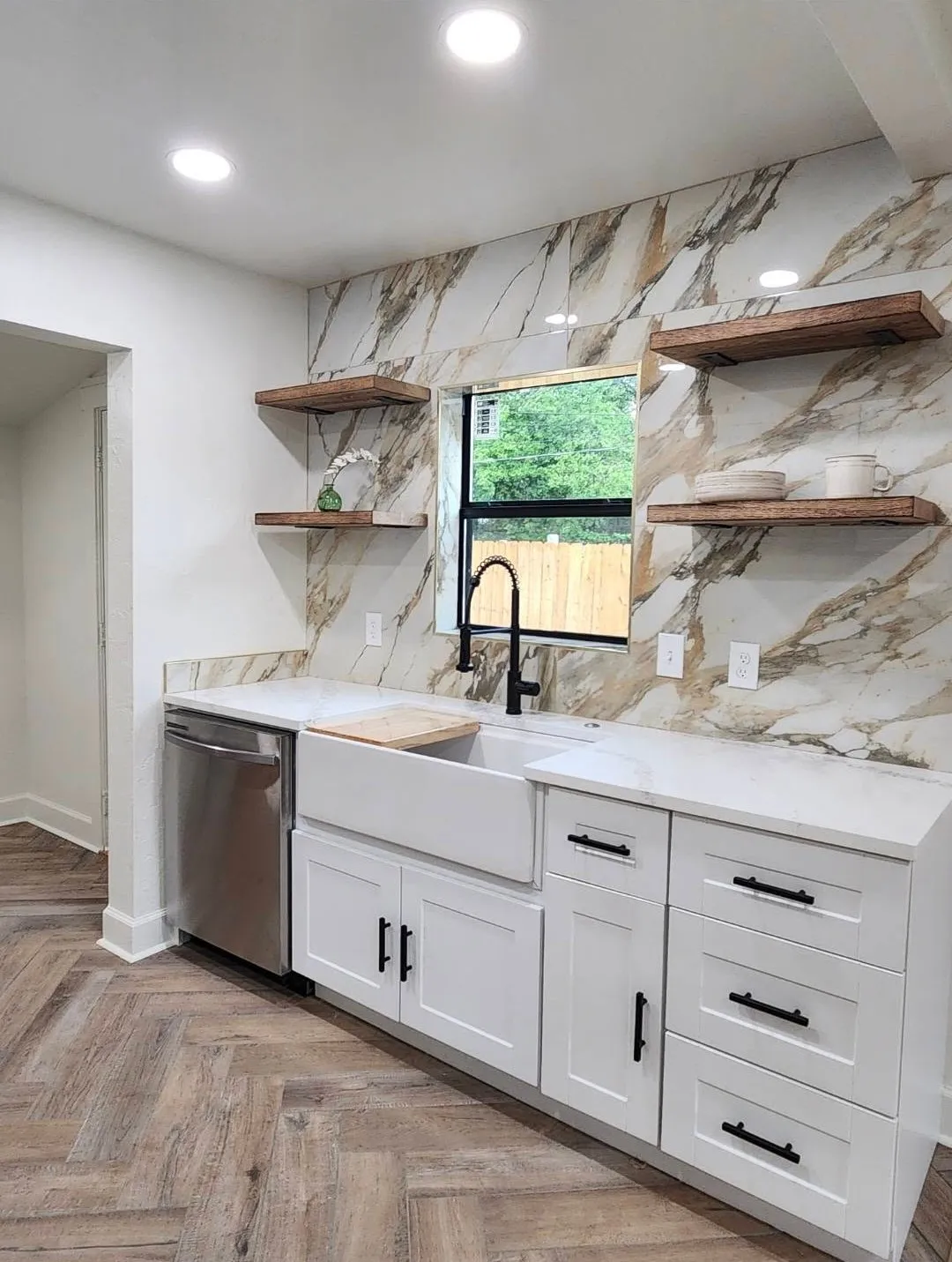 Farmhouse sink kitchen with marble slab backsplash and floating shelves in Oklahoma City
